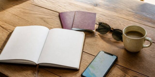 Notitieboek en reisbenodigdheden op tafel tijdens het plannen van een vakantie