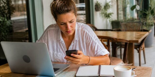 Vakanties vergelijken op een laptop en telefoon bij een cafétafel